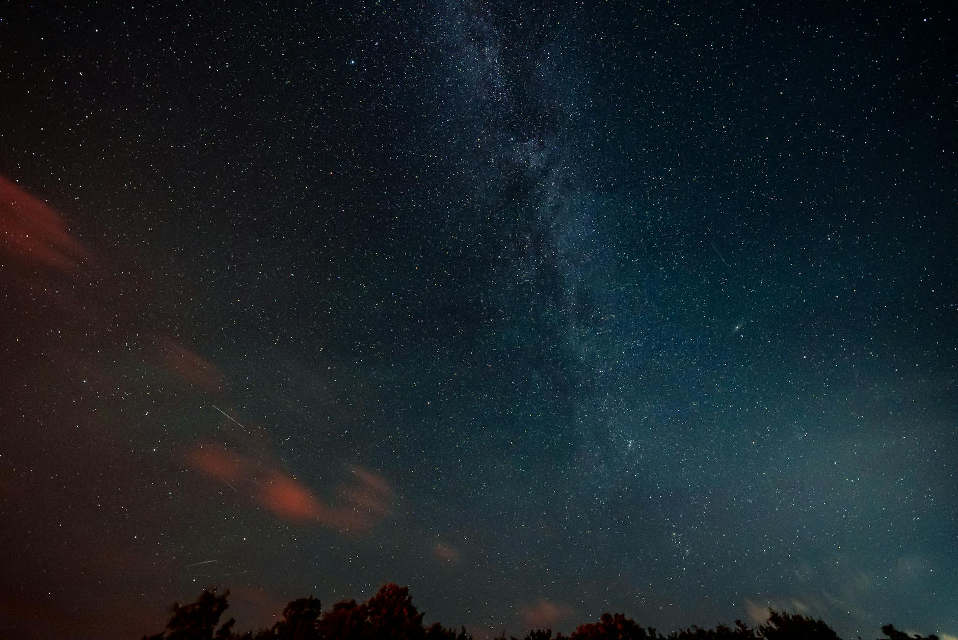 Droga Mleczna i gwiazdy na nocnym niebie nad ciemnym horyzontem