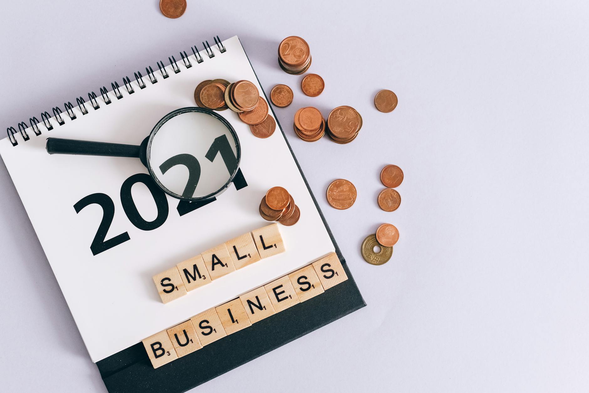 Kalendarz 2021, monety i napis small business obok lupy