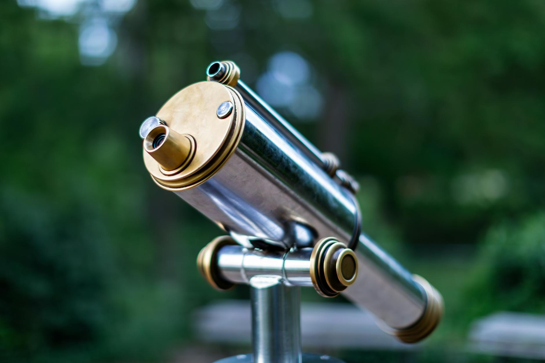 Mosiężny teleskop ustawiony na zewnątrz na tle rozmytego krajobrazu
