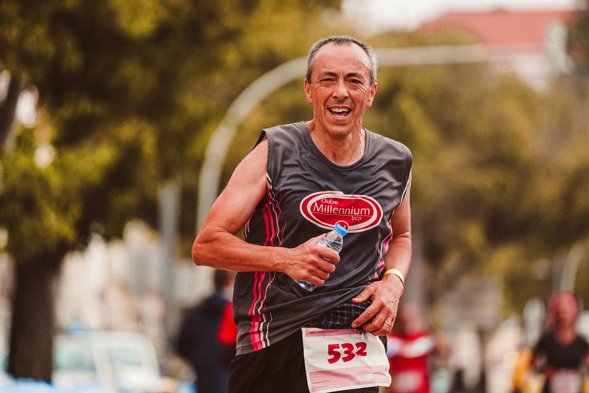 Biegacz amator z butelką wody podczas maratonu na świeżym powietrzu