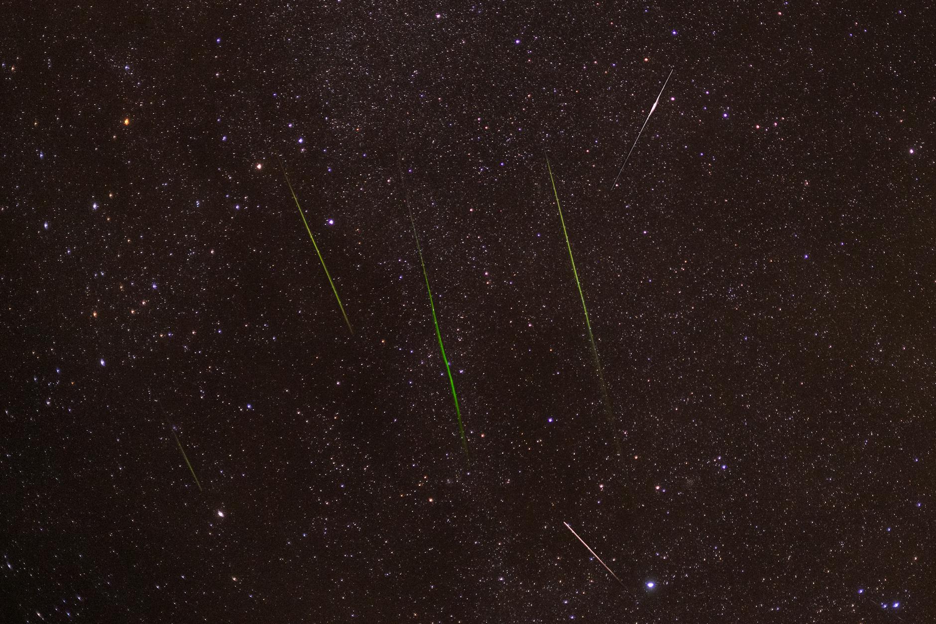 Jasne meteory przecinające gwiaździste nocne niebo podczas roju
