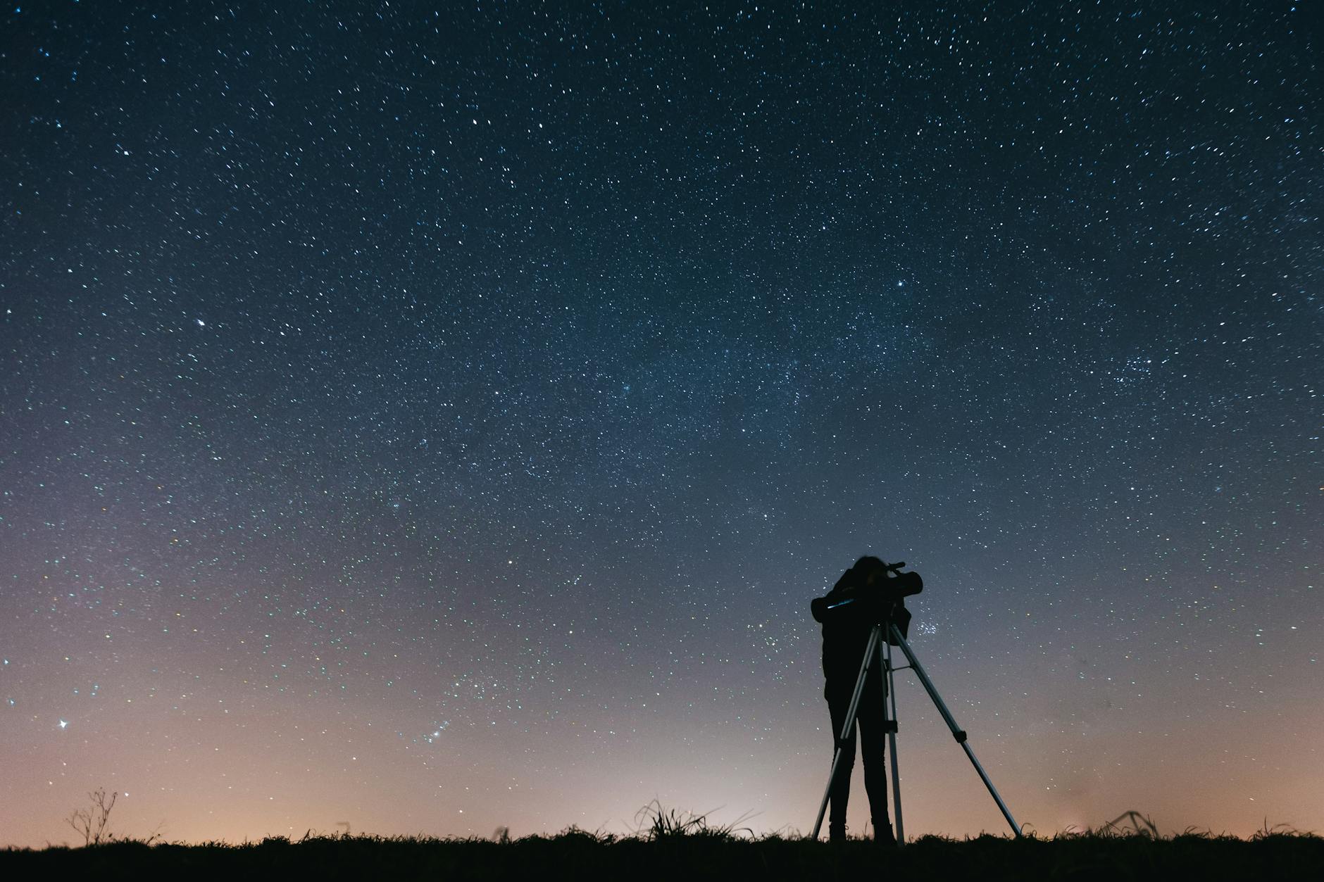 Początkujący obserwator patrzy przez teleskop na gwiaździste nocne niebo